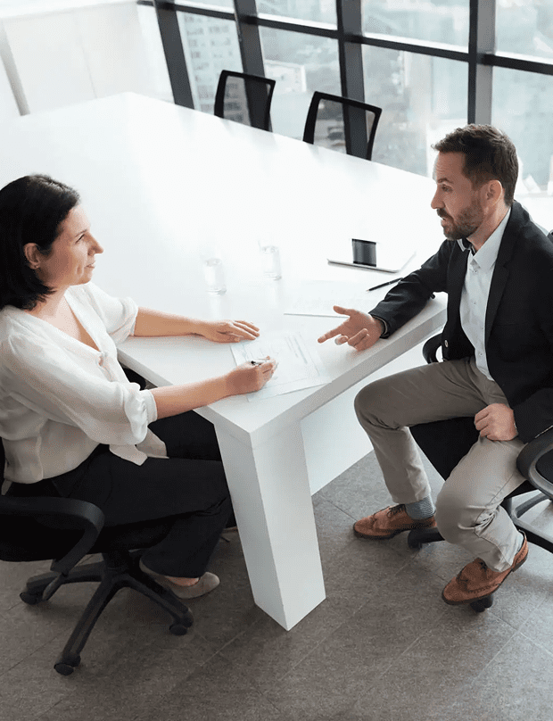 Business meeting between two colleagues discussing work at a modern office desk.